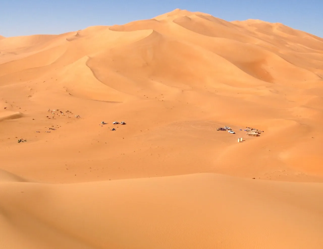 Figure 5: A close-up of a star dune complex, with several slip faces indicating more than one wind direction. Notice at the bottom of the complex (see the camp) there is a small inter-dune lake deposit.This camp was used as a base-camp to supply the camel trip that was organised for a number of scientific surveys of the palaeo-lakes that lie deep within the dunes.(Photo courtesy of Franco-Libyan Palaeontological Project.)