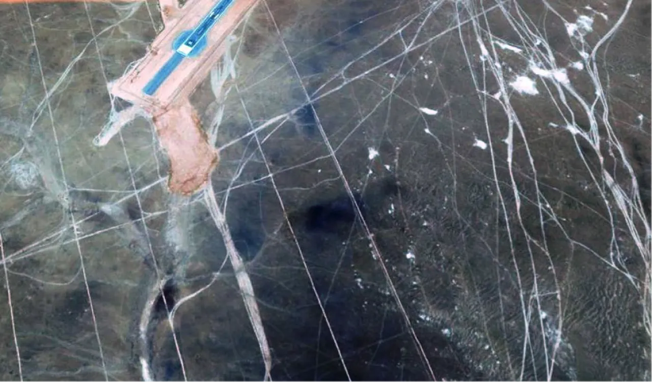 Satellite image of part of Messak Sattafet Plateau surface at El Fil Oil Field.  Part of the airstrip is visible in the northern part of the image. Messk Sattafet is one of the fragile heritage areas in Libya, with hundreds of engravings on the sides of various wadis and millions of archaeological artifacts scattered on the surface of the plateau and wadi edges. Many of these artifacts were lost mainly as a result of oil exploration and exploitation activities in the last two decades. Oil activities in the Messak not only caused direct loss of artifacts, but also opened many new tracks through the difficult terrain, which enabled other visitors and tourists to reach all the areas that previously were protected by their inaccessible position.