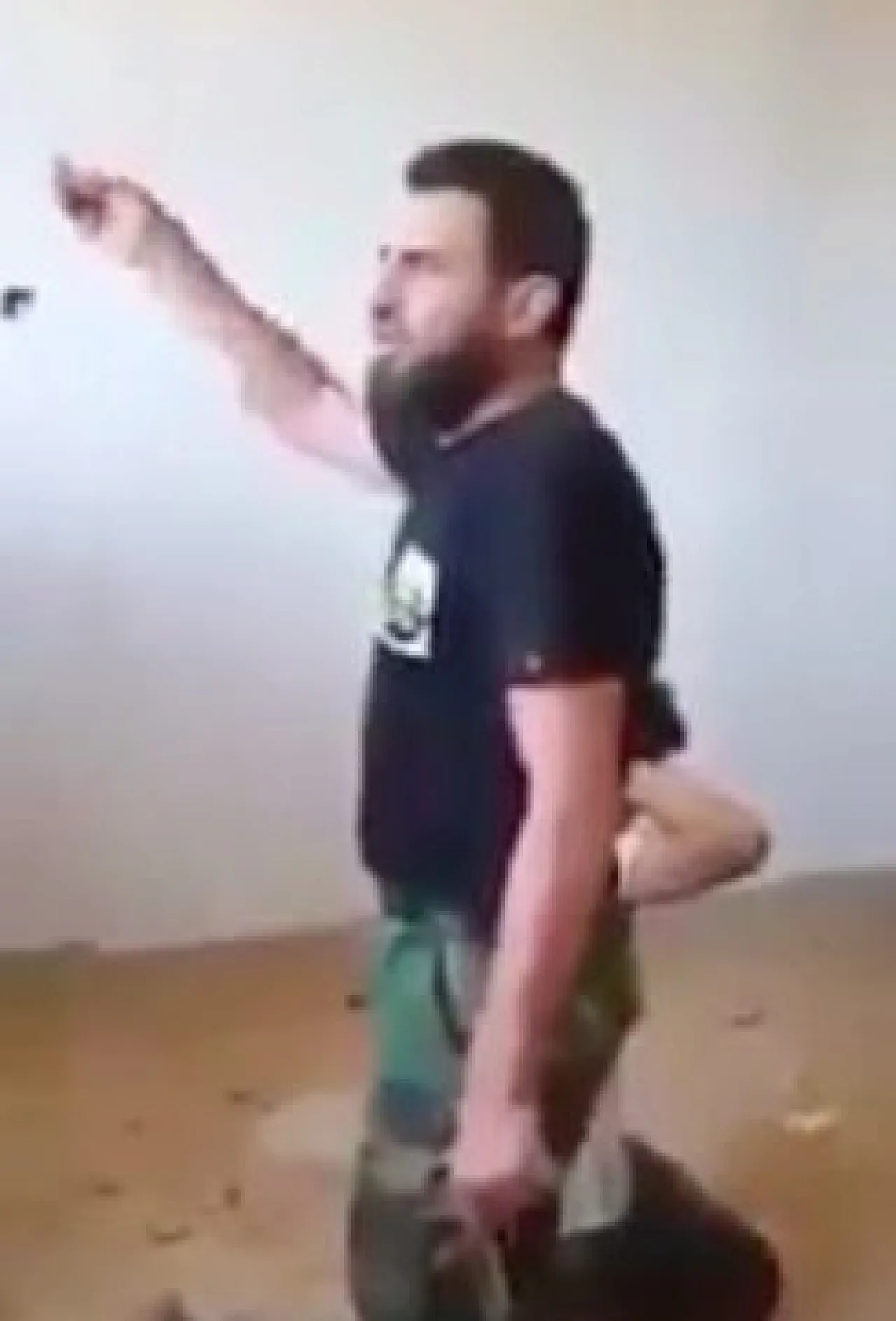 The gunman speaking while his victim kneels behind him (Social media screen grab) 